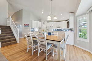 Dining room featuring a notable chandelier, sink, high vaulted ceiling, and light hardwood / wood-style floors