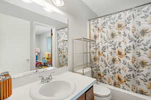 Full bathroom featuring shower / bath combination with curtain, toilet, and vanity