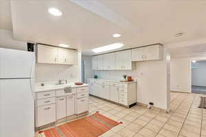 Kitchen featuring white cabinets, white refrigerator, and light tile flooring