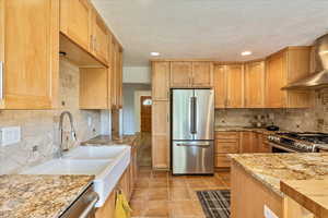 Kitchen with premium appliances, a textured ceiling, and tasteful backsplash