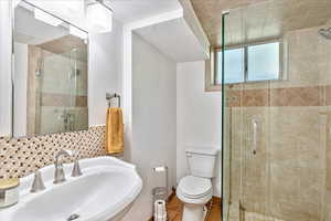 Bathroom with tile flooring, walk in shower, sink, and toilet