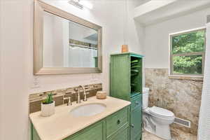 Bathroom featuring tasteful backsplash, vanity with extensive cabinet space, tile walls, tile floors, and toilet