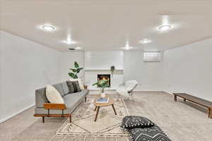 Living room with carpet floors, a fireplace, and brick wall