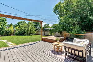 Deck featuring a lawn and a covered hot tub