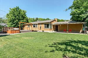 Back of property with a patio area, a hot tub, and a yard