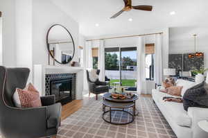 Living room featuring ceiling fan, a tile fireplace, and wood-type flooring