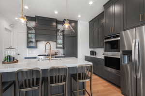 Kitchen featuring light stone countertops, pendant lighting, light wood-type flooring, and stainless steel appliances