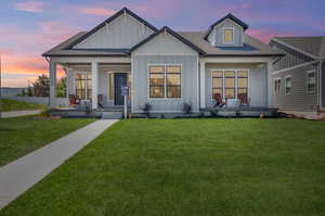 View of front of property with covered porch and a lawn