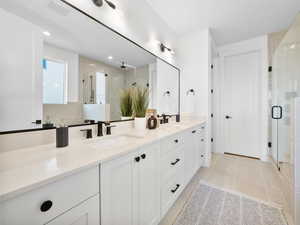 Bathroom featuring double sink vanity, tile patterned flooring, and a shower with shower door