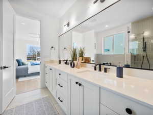 Bathroom with tile patterned flooring, a tile shower, and double sink vanity