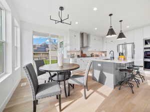 Dining room with sink, light hardwood / wood-style flooring, and a chandelier