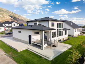 Back of house with a mountain view, a patio, and a yard