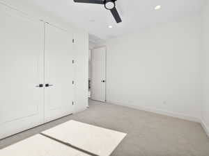 Unfurnished bedroom with ceiling fan, a closet, and light colored carpet