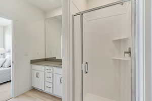 Bathroom featuring a shower with door, hardwood / wood-style flooring, and oversized vanity