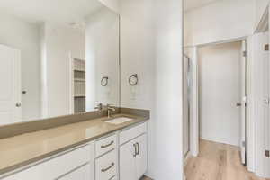 Bathroom featuring a shower with door, vanity, and wood-type flooring