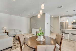 Dining room with light hardwood / wood-style floors and a textured ceiling