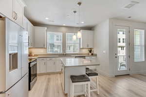 Kitchen featuring light hardwood / wood-style floors, a kitchen island, range, sink, and white refrigerator with ice dispenser