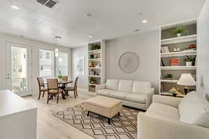 Living room with light hardwood / wood-style floors, a textured ceiling, and built in features