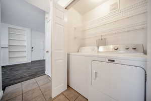 Clothes washing area with washer and clothes dryer and light hardwood / wood-style floors