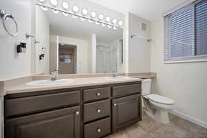 Master Bathroom with tile flooring, dual vanity, and toilet