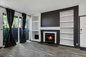 Unfurnished living room featuring built in features and wood-type flooring