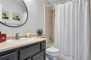 Full bathroom with shower / bathtub combination with curtain, vanity, and toilet