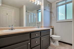 Bathroom with tile flooring, dual vanity, and toilet