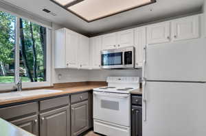 Kitchen featuring gray cabinetry, white cabinets, sink, and white appliances