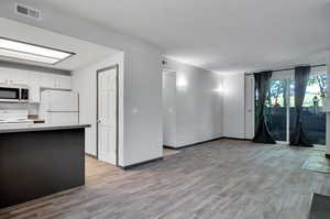 Kitchen with white appliances, white cabinets, and light hardwood / wood-style floors