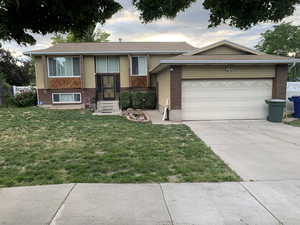 View of front of property with a garage and a front lawn