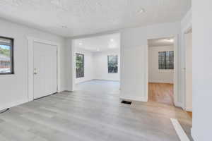 Unfurnished room with a textured ceiling and light wood-type flooring