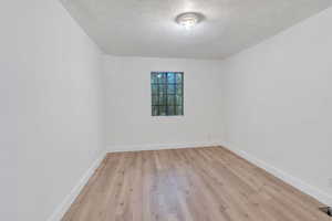 Unfurnished room with light hardwood / wood-style flooring and a textured ceiling