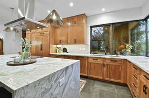 Kitchen featuring hanging light fixtures, island exhaust hood, backsplash, a healthy amount of sunlight, and sink