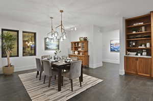 Dining area with a notable chandelier, track lighting, and dark tile flooring