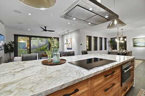 Kitchen with ceiling fan, tile flooring, black electric stovetop, pendant lighting, and oven