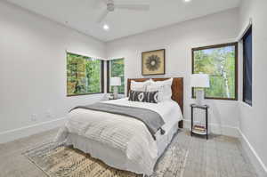 Carpeted bedroom with ceiling fan and multiple windows