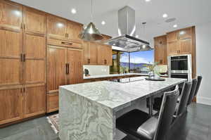 Kitchen with decorative light fixtures, island range hood, a center island, and double oven