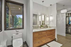 Bathroom with double vanity, tile flooring, a chandelier, and toilet