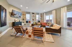 Living room featuring built in features, concrete floors, and ceiling fan