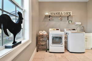 Laundry room featuring sink, washer and dryer, cabinets, and light tile floors