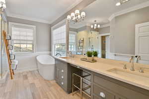 Bathroom featuring crown molding, double vanity, a notable chandelier, and shower with separate bathtub