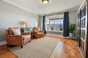 Living area with ornamental molding and hardwood / wood-style flooring