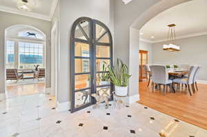 Tiled foyer entrance featuring a water view, french doors, and crown molding