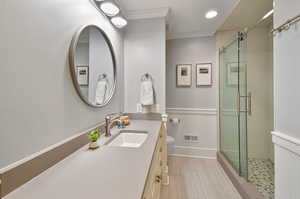 Bathroom featuring an enclosed shower, tile floors, ornamental molding, toilet, and large vanity