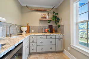 Kitchen with sink, ornamental molding, tasteful backsplash, and light tile floors