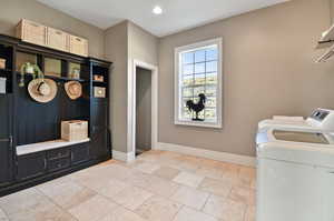 Laundry room with washer and clothes dryer and light tile floors