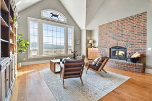 Living room with brick wall, a brick fireplace, a wealth of natural light, and light wood-type flooring