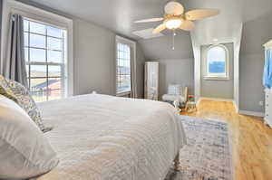 Bedroom with ceiling fan, vaulted ceiling, hardwood / wood-style floors, and multiple windows