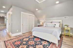 Bedroom featuring wood-type flooring, a closet, and lofted ceiling