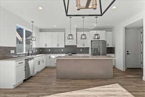 Kitchen featuring stainless steel appliances, tasteful backsplash, hardwood / wood-style floors, and a kitchen island